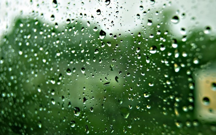 Raindrops on glass with green background