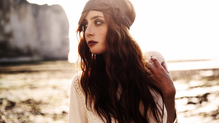 Woman with long brown hair and headband on beach