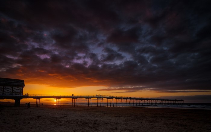 Sunset over a pier on a beach