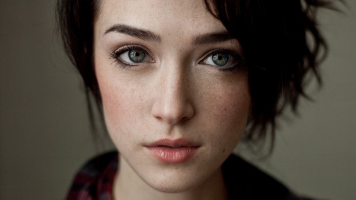 Close-up portrait of a young woman with freckles and blue eyes