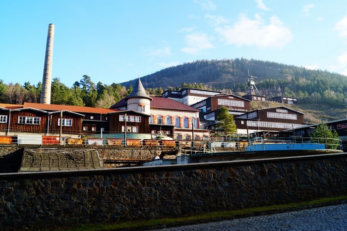 Mine buildings on a hillside with a tall smokestack