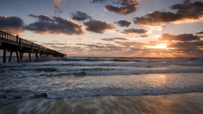 Sunrise over the ocean with a pier