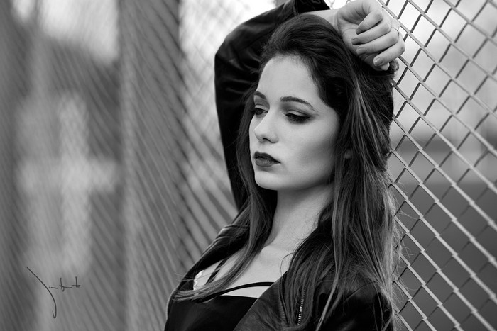 Woman leaning against a chain-link fence
