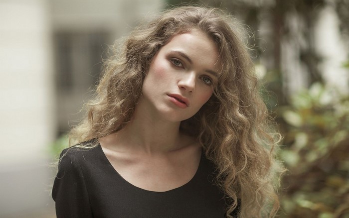 Woman with curly blonde hair in a black top