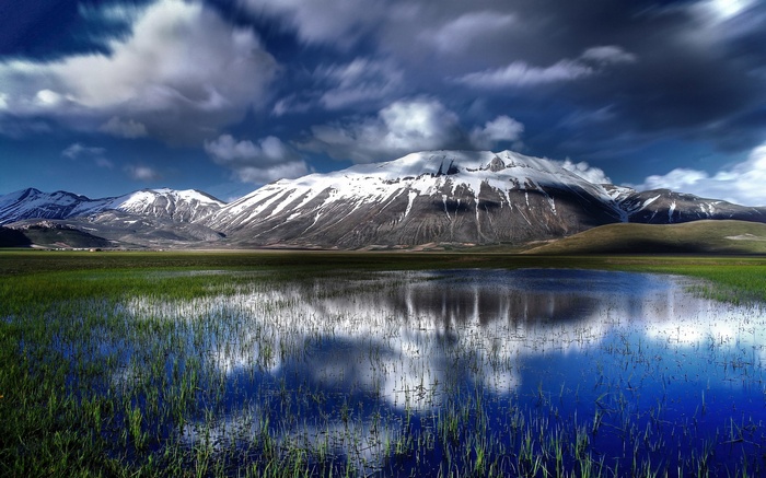 Snow-capped mountains reflected in a flooded field