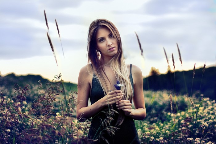 Woman holding a flower in a field