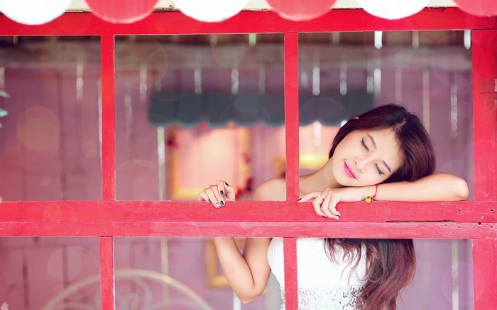 Woman resting her head on a red window frame