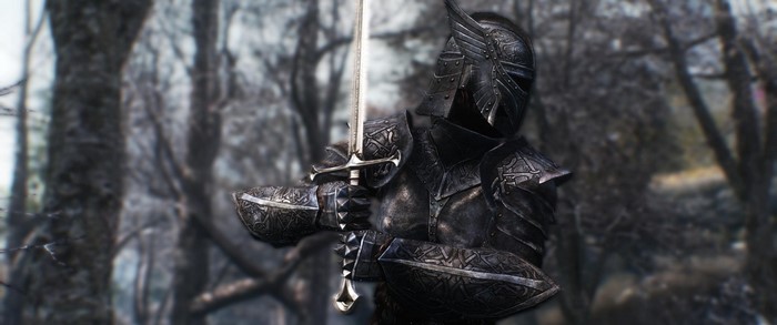 Knight in black armor holding a sword in a forest