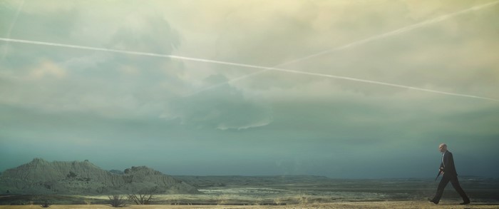 Agent 47 from Hitman walking in a desert landscape
