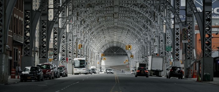 Cars and bus under a large metal bridge structure