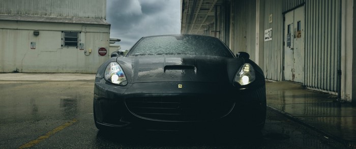 Black Ferrari sports car on wet asphalt