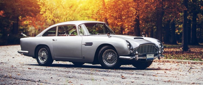 Silver Aston Martin DB5 parked on a road in autumn