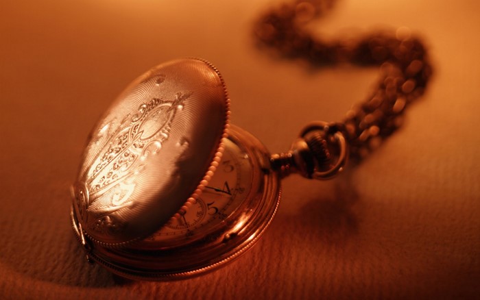 Close-up of an ornate pocket watch with a chain
