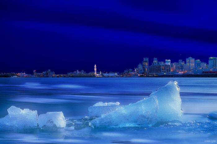 Ice chunks in frozen river with city skyline at night