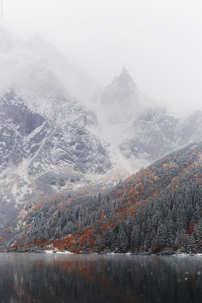 Snowy mountains and lake with autumn trees