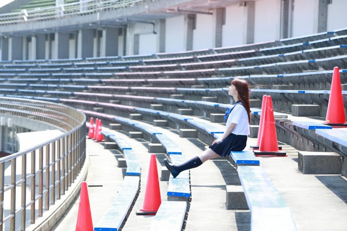 Woman in school uniform sitting in stadium