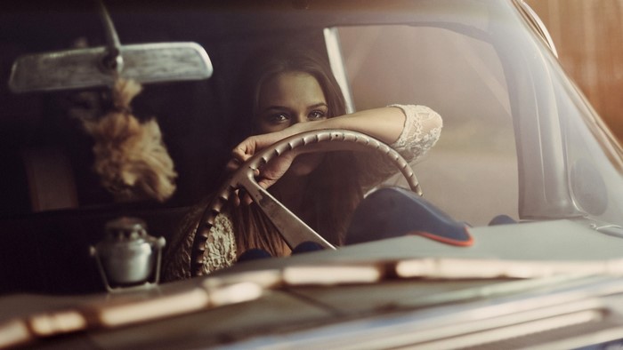 Woman in vintage car holding steering wheel