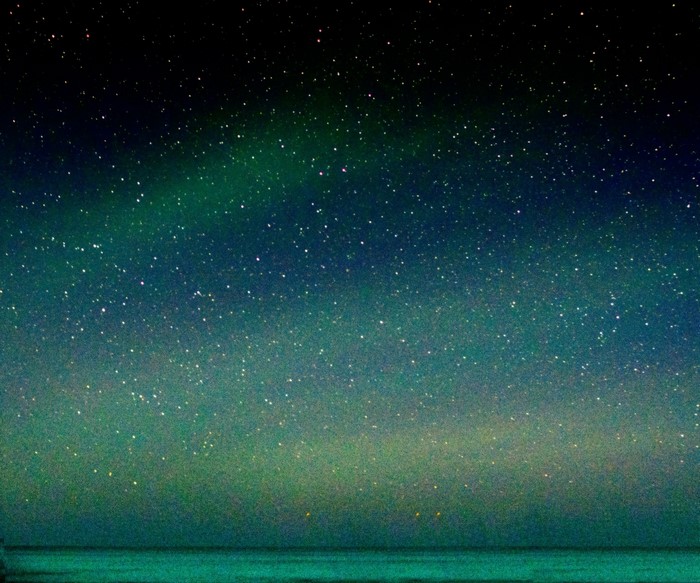 Starry night sky over the ocean with aurora