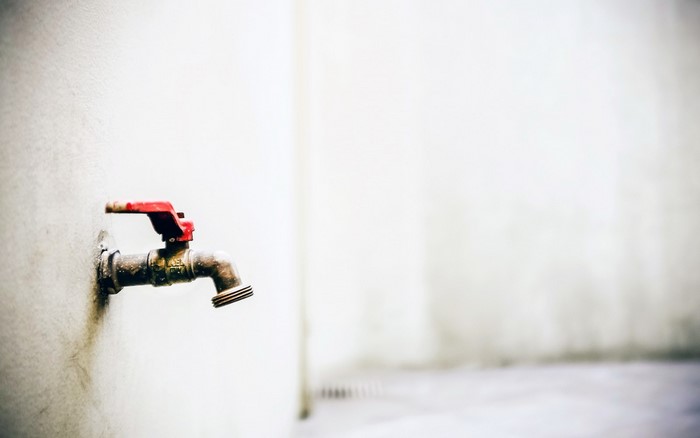 Red handled faucet on a white wall