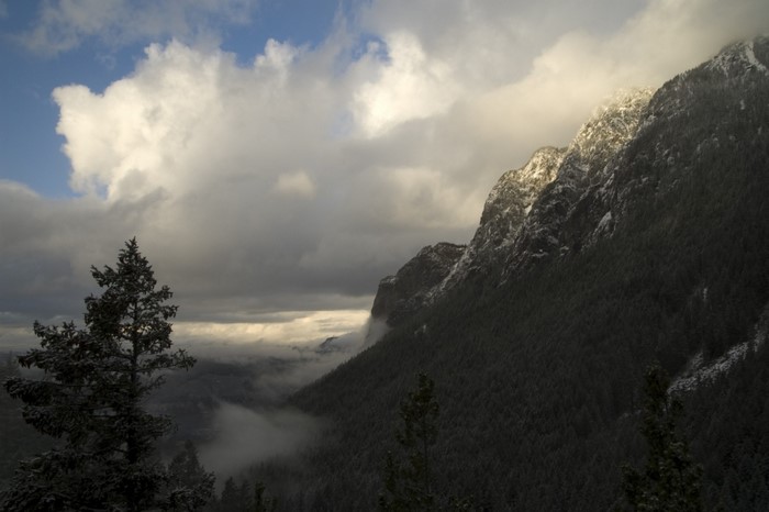 Snowy mountain ridge with clouds and forest
