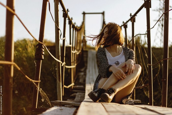 Woman sitting on a wooden suspension bridge
