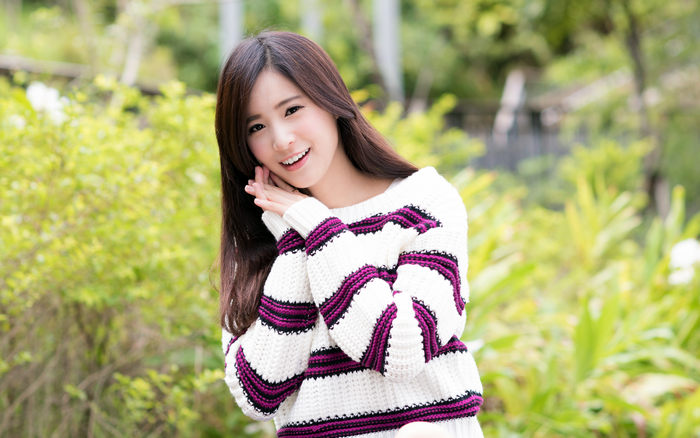 Young Asian woman smiling outdoors in a striped sweater