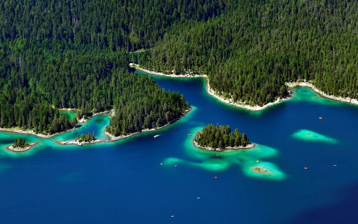 Aerial view of a turquoise lake surrounded by a dense green forest