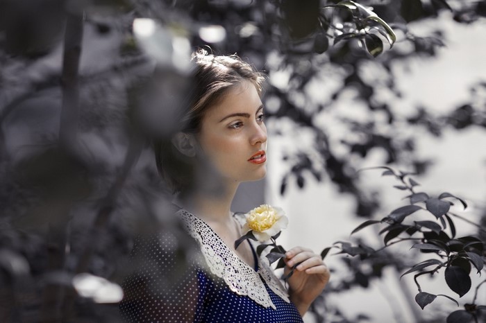 Woman holding a yellow rose in a garden