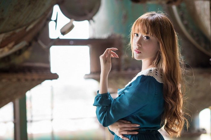 Asian woman in blue dress posing in industrial setting