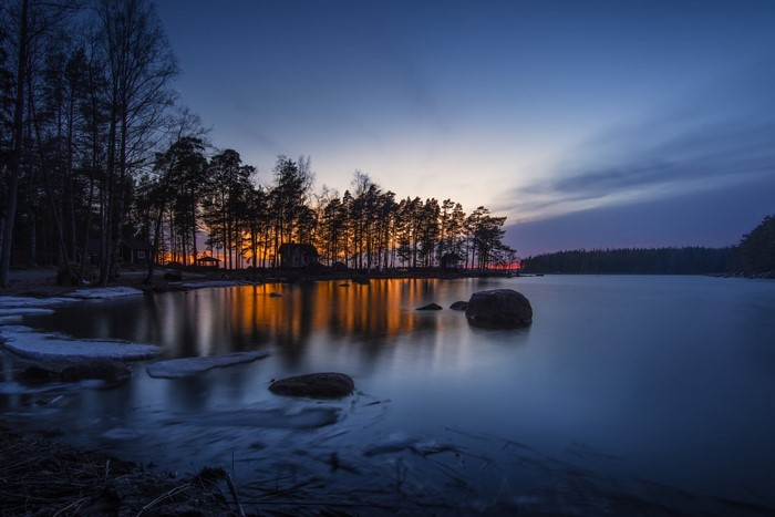 Sunset over a calm lake with trees and reflections