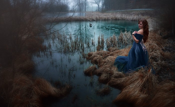Woman in blue dress by a lake in autumn