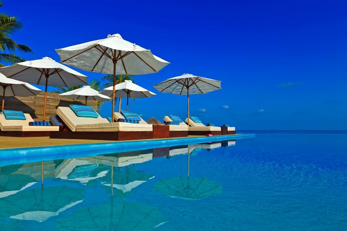 Infinity pool with lounge chairs and umbrellas by the ocean