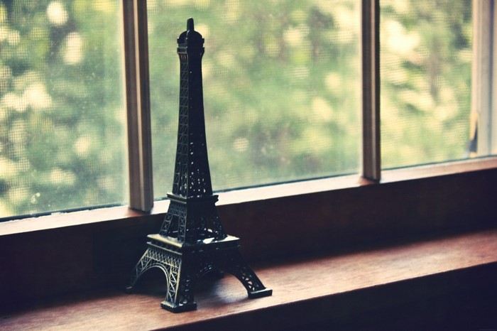 Eiffel Tower replica on a windowsill with trees outside