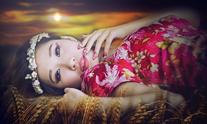 Asian woman with floral dress in wheat field at sunset