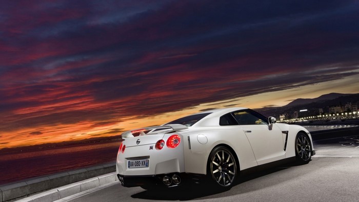 White Nissan GT-R parked by the sea at sunset