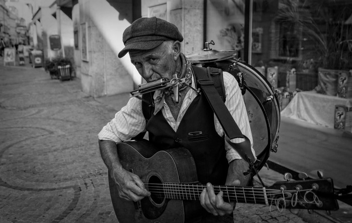 Street musician playing guitar and harmonica