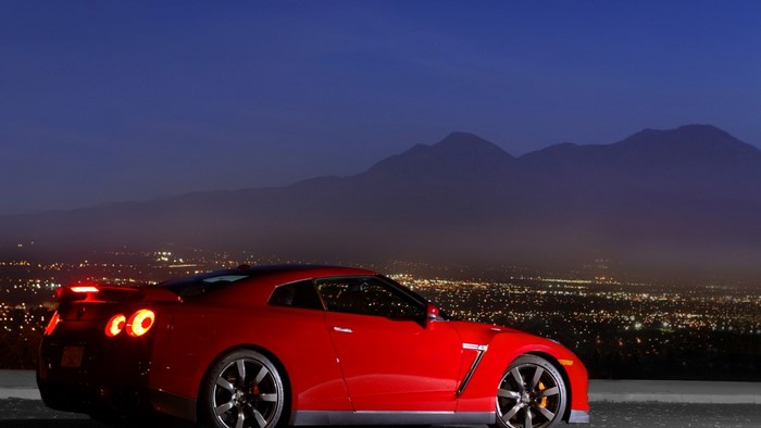 Red Nissan GT-R parked overlooking a city at night