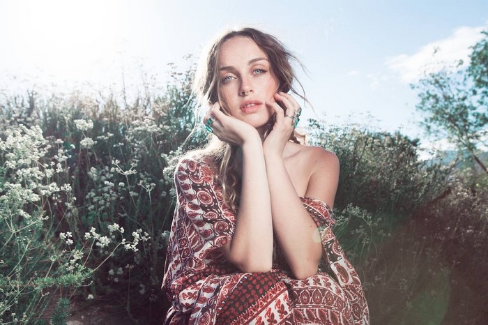 Zella Day sitting in a field of flowers