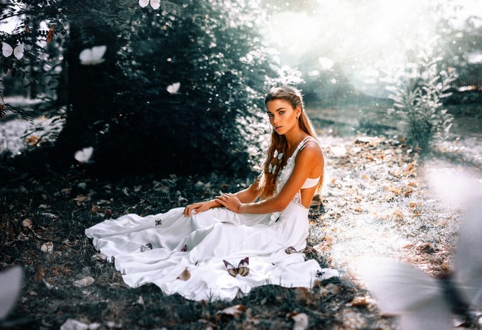 Woman in white dress with butterflies in sunlight