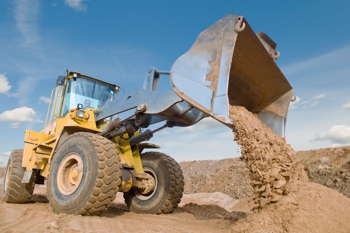 Yellow front loader dumping sand on a construction site