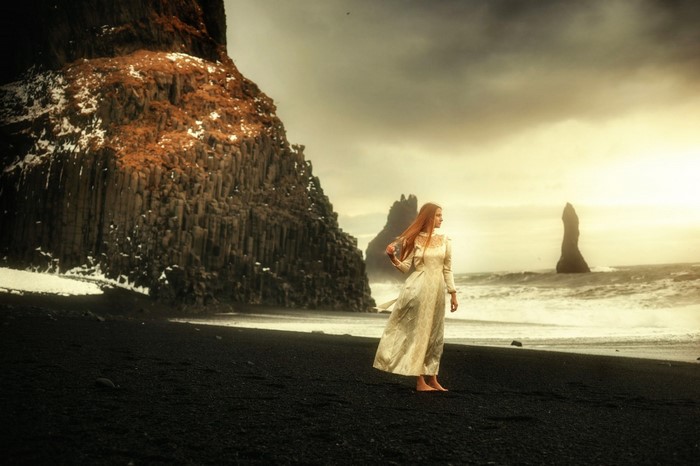 Woman in a dress on a black sand beach