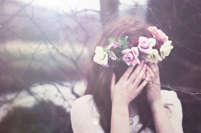 Woman with flower crown covering face outdoors