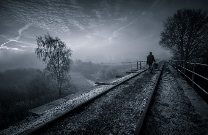 Man walking on a foggy railway bridge