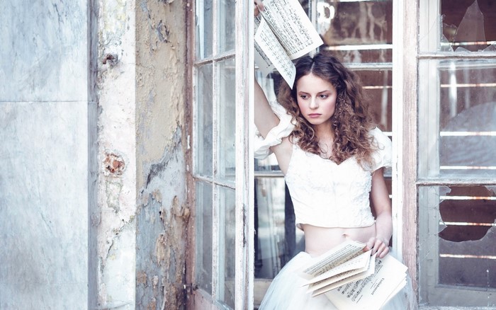 Woman in white dress holding musical notes by a broken window