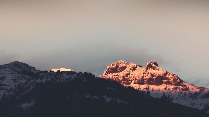Snow-covered mountains at sunrise with golden light