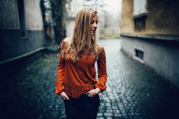 Woman in orange sweater standing in alley