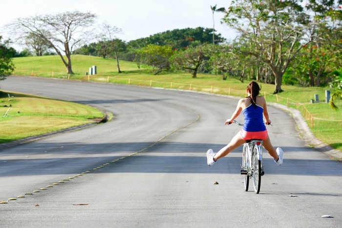 Woman cycling with legs spread on a road