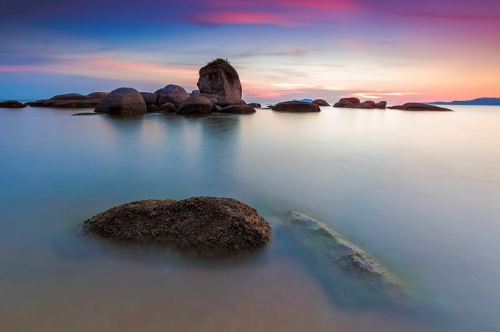 Sunset over a rocky sea coast with calm water