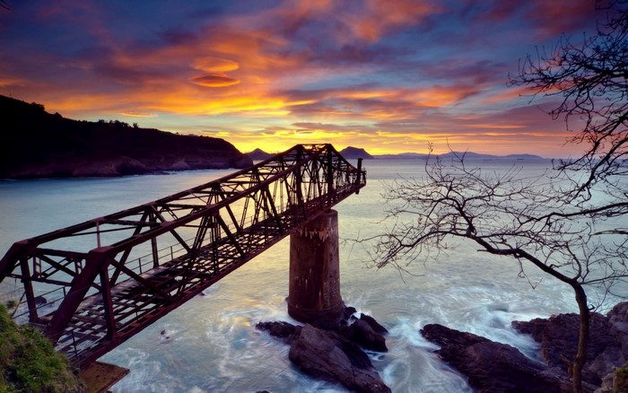 Abandoned bridge over the sea at sunset