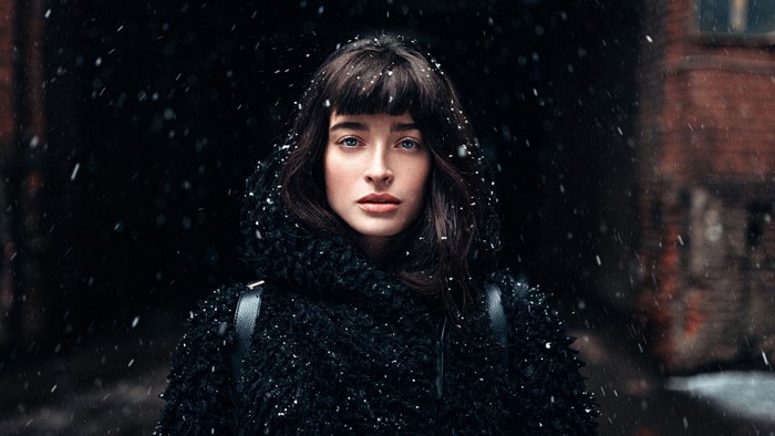 Woman in black coat in falling snow